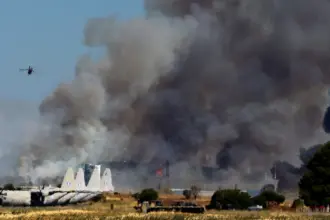 Tanagra Air Base is surrounded with heavy black smoke, as flames and other aircraft can be seen at the Athens Flying Week show.
