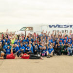 Image shows a large number of people at the Haul for Hope fundraising event at Calgary International Airport with a WestJet aircraft behind them