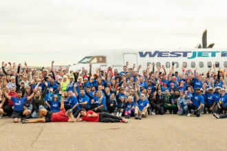 Image shows a large number of people at the Haul for Hope fundraising event at Calgary International Airport with a WestJet aircraft behind them