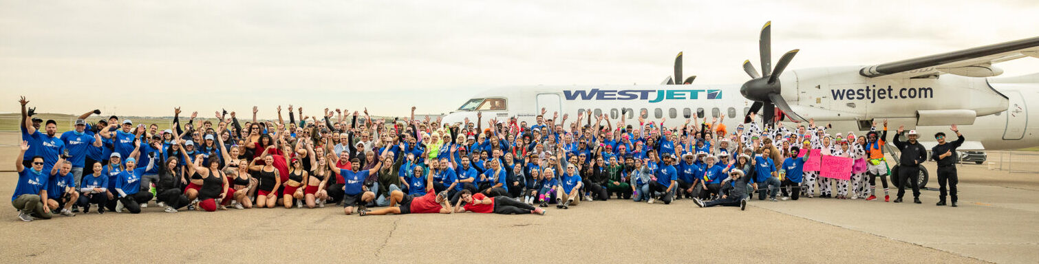 Image shows a large number of people at the Haul for Hope fundraising event at Calgary International Airport with a WestJet aircraft behind them
