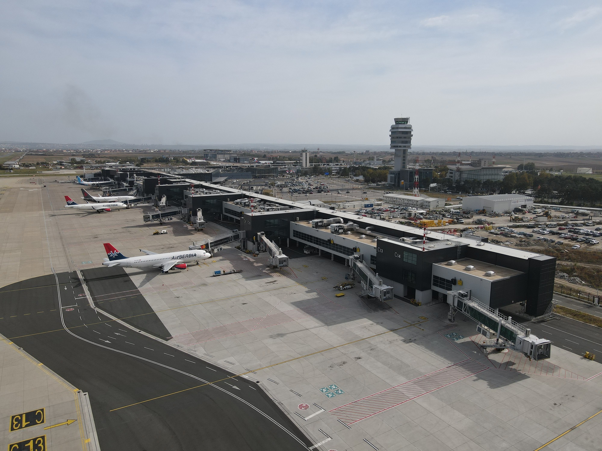 Belgrade Nikola Tesla Airport (BEG) on a cloudy day. Three white planes are sat next to an airport terminal.