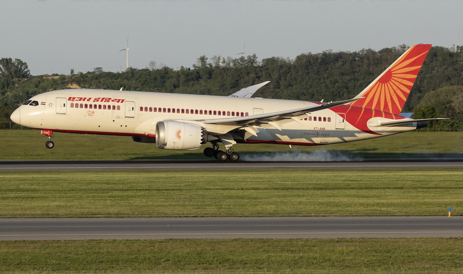 The red and white Boeing 787-8 Dreamliner VT-ANB taking of from a runway behind a grassy verge.