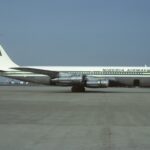 A green and white Nigeria Airways jet sat on a runway in front of a clear blue sky.