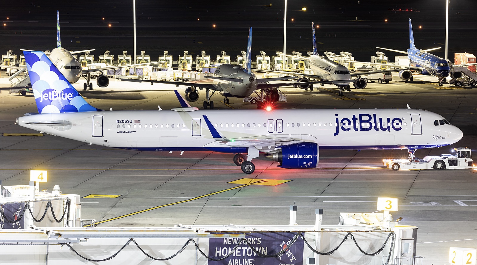 A white and blue jetBlue aircraft sat on a runway at John F. Kennedy International Airport (JFK) at sunset.