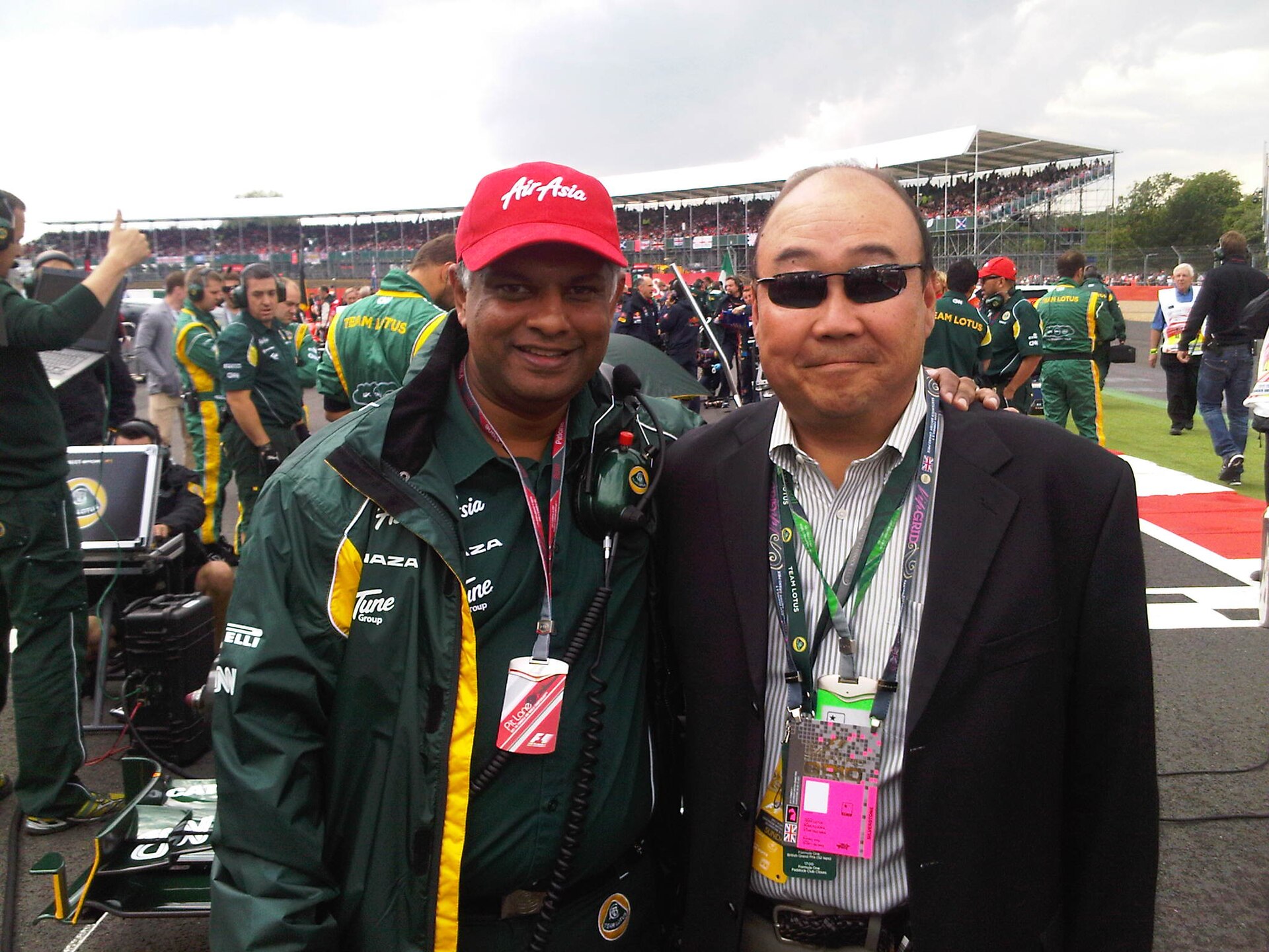 AirAsia CEO Tony Fernandes stood in a red AirAsia cap, and a green Team Lotus F1 team jacket, stood next to Russ Fujioka.