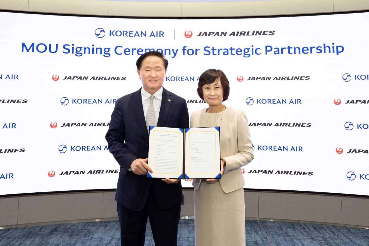 Korean Air and Japan Airlines sign a memorandum that will secure a strategic partnership. On the left, Korean Air Vice Chairman Keehong Woo stands holding the signed papers along with JAL President Tottori on the right.