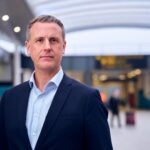 Image shows Mark Johnston, COO of Gatwick Airport in the foreground with a blurred airport in the background