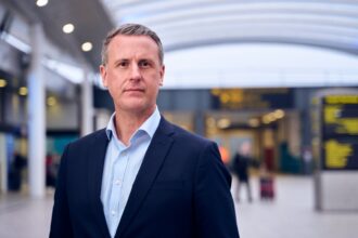 Image shows Mark Johnston, COO of Gatwick Airport in the foreground with a blurred airport in the background