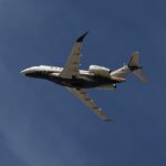 Photo depicting Flexjet Embraer Praetor 600 flying overhead against a blue sky.