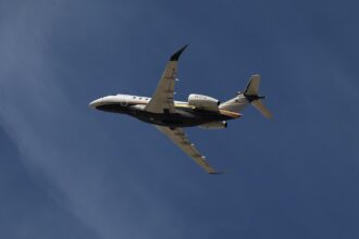 Photo depicting Flexjet Embraer Praetor 600 flying overhead against a blue sky.