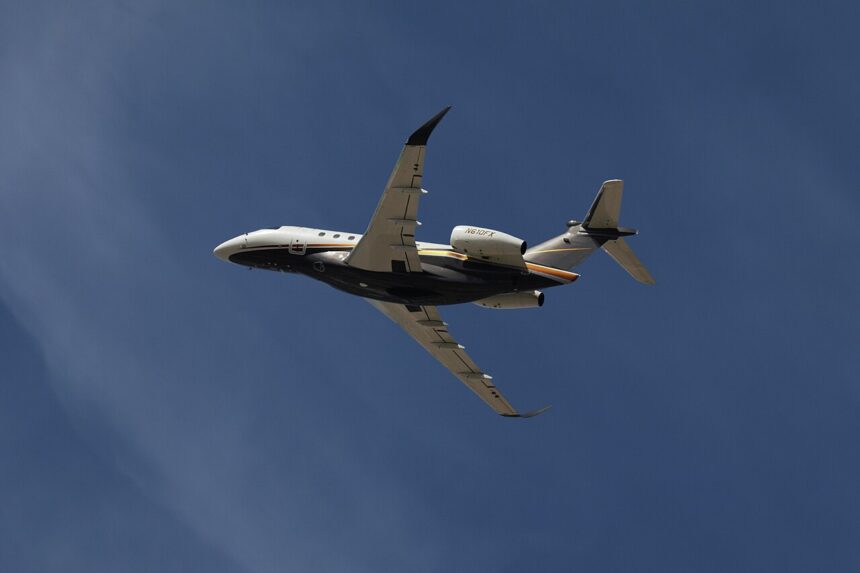 Photo depicting Flexjet Embraer Praetor 600 flying overhead against a blue sky.