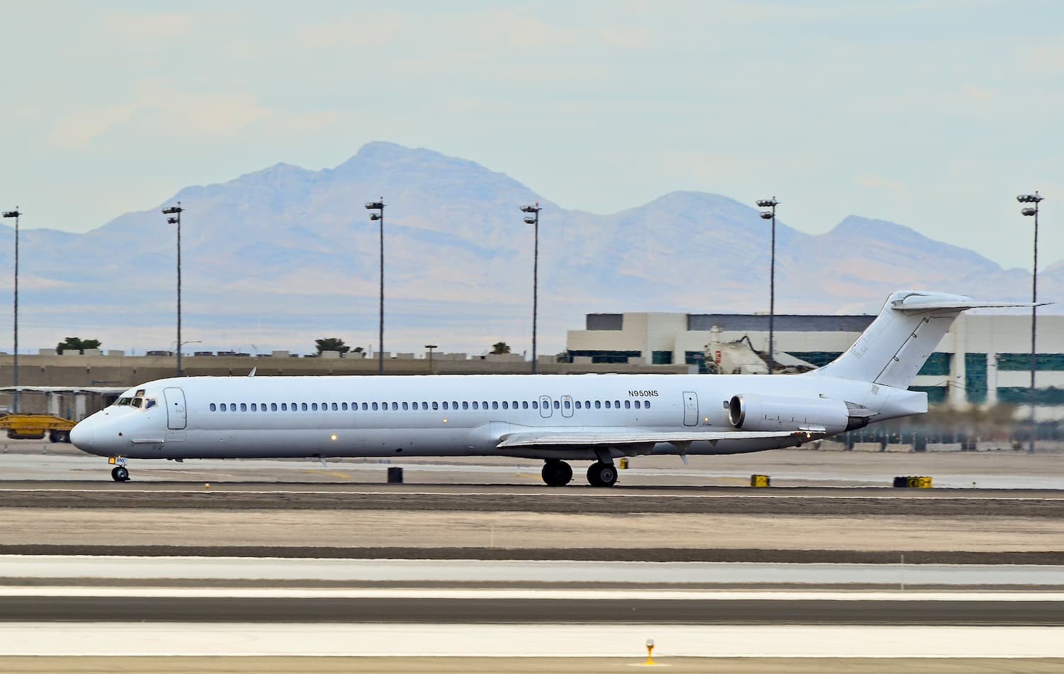 Image shows a McDonnell Dougal MD-83 on a runway with mountains in the background