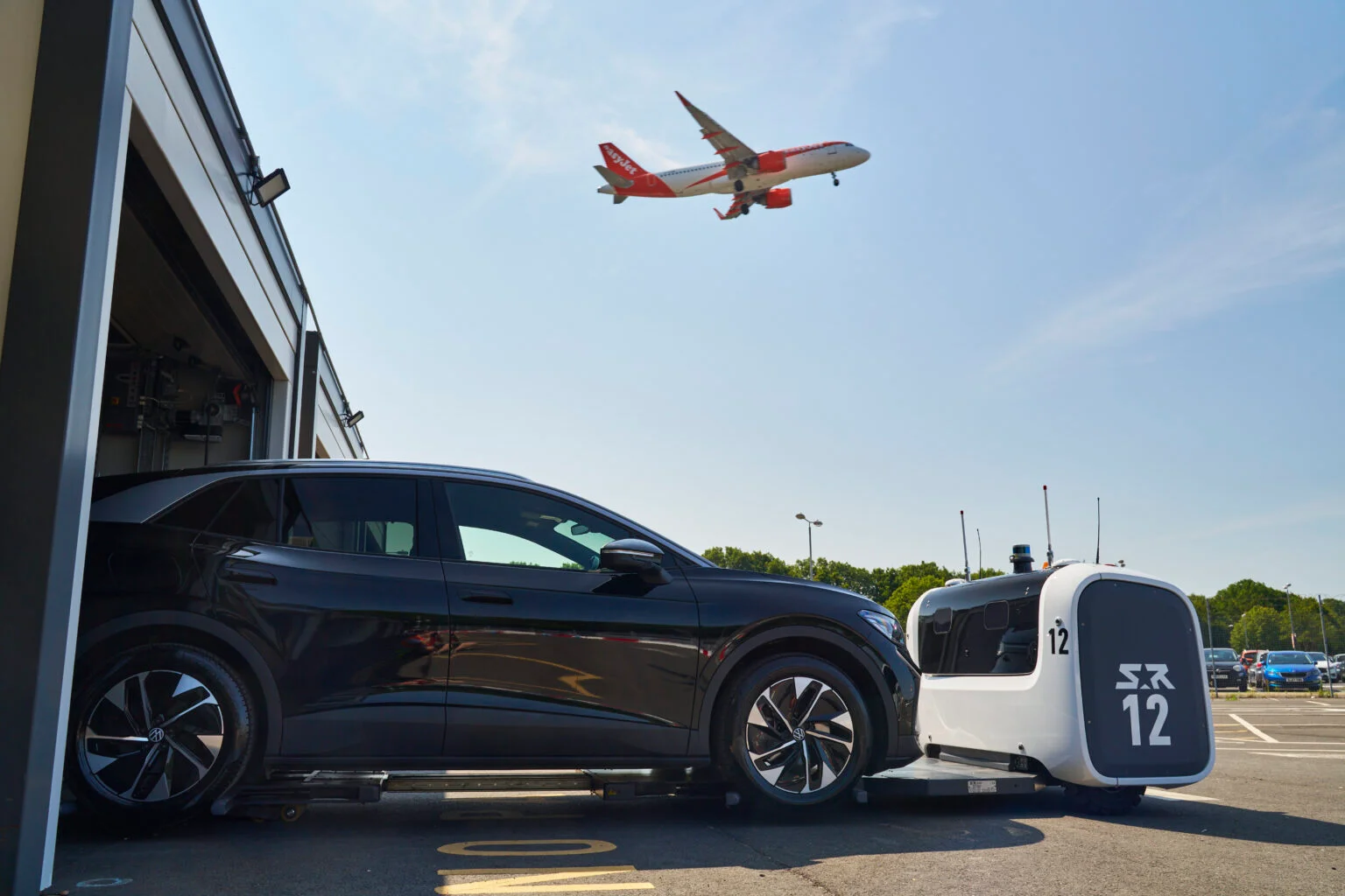 A black Volkswagen is pictured being lifted by one of the robots, and directed into one of the secure units as a plane flies overhead.