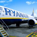 A Ryanair Boeing 737-800 parked on an airport terminal, with the stairs lowered.