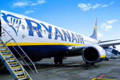 A Ryanair Boeing 737-800 parked on an airport terminal, with the stairs lowered.