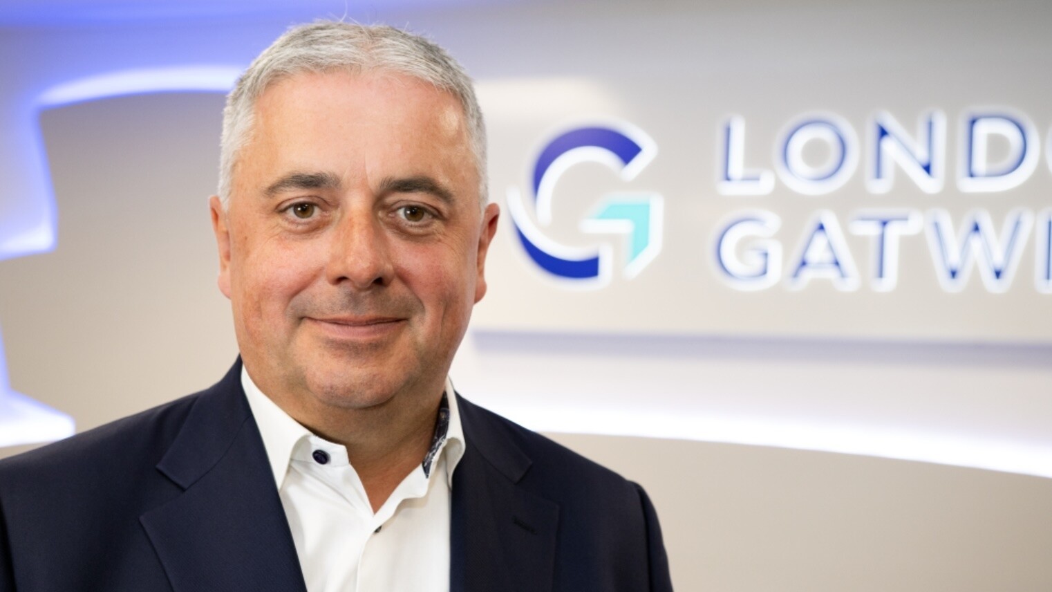 Image shows Stewart Wingate, the new chair of the board at Gatwick Airport in the foreground with a blurred airport logo in the background