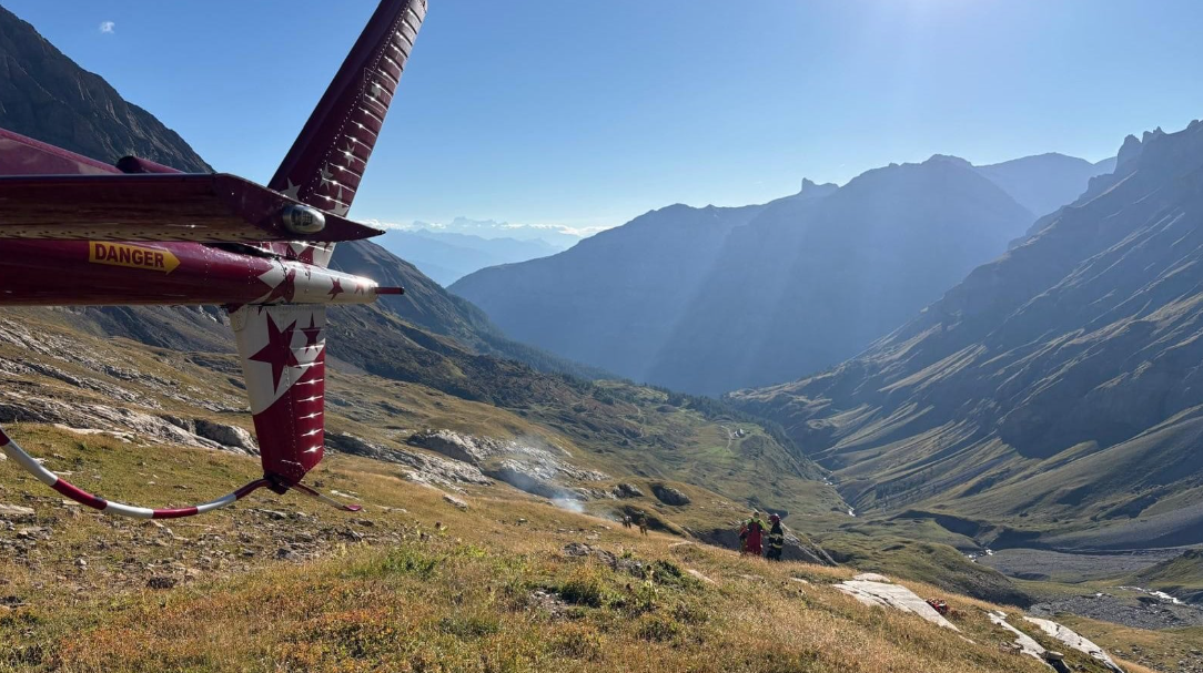 Image shows the crash site with the tail of the plane with smoke rising in the background