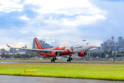 Vietjet aircraft on a green grass field with buildings at the back