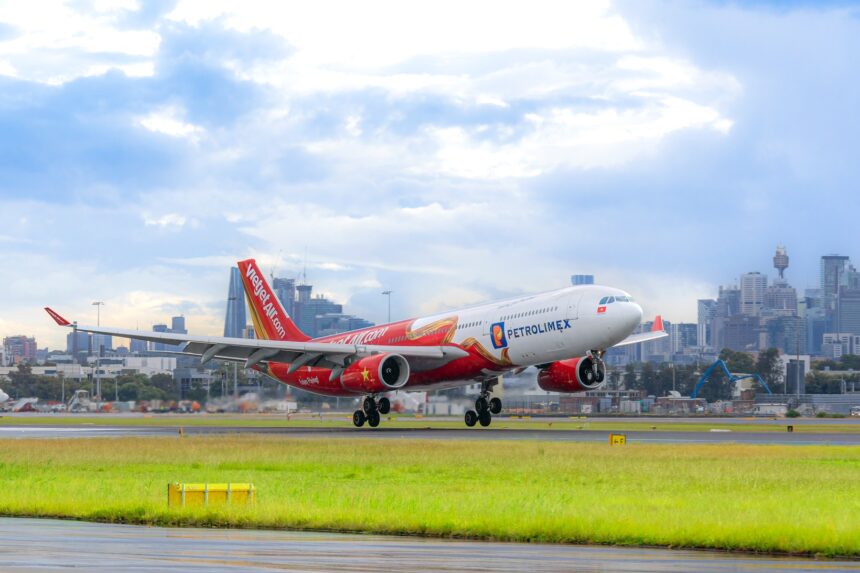Vietjet aircraft on a green grass field with buildings at the back