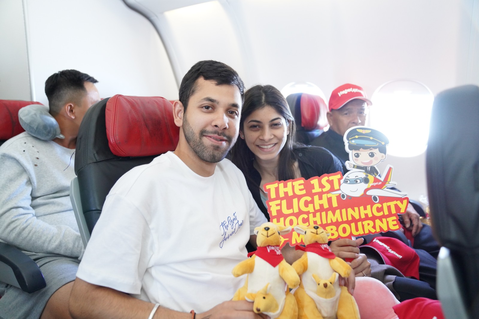 Two passengers inside a Vietjet airline holding a sign, 