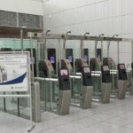 Barriers at border control within an airport terminal, a sign can be seen next to the electronic barriers showing information about the system.