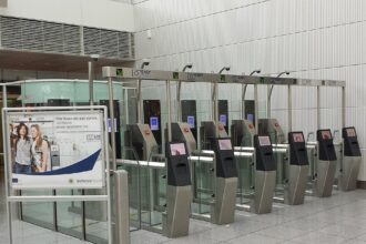 Barriers at border control within an airport terminal, a sign can be seen next to the electronic barriers showing information about the system.