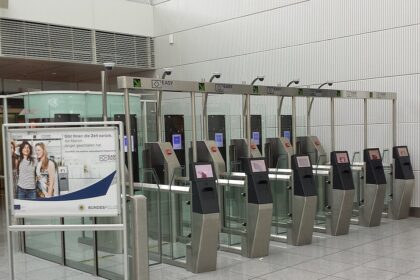 Barriers at border control within an airport terminal, a sign can be seen next to the electronic barriers showing information about the system.