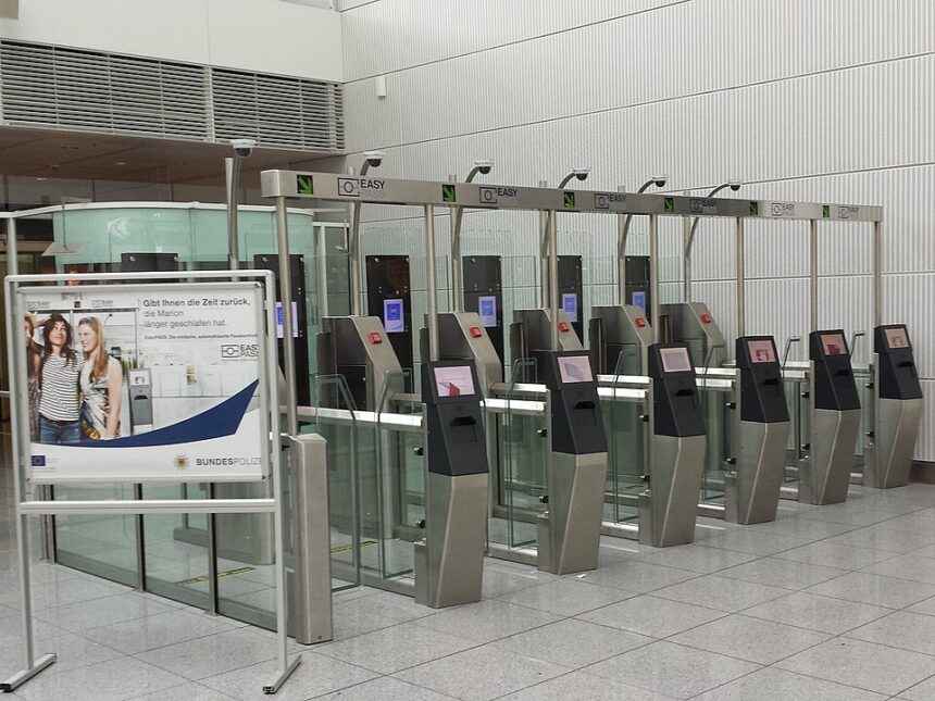 Barriers at border control within an airport terminal, a sign can be seen next to the electronic barriers showing information about the system.