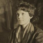Amelia Earhart sitting down and slightly smiling away from camera