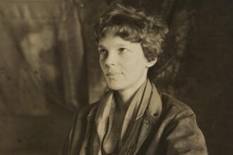 Amelia Earhart sitting down and slightly smiling away from camera