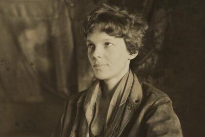 Amelia Earhart sitting down and slightly smiling away from camera