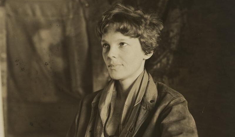 Amelia Earhart sitting down and slightly smiling away from camera