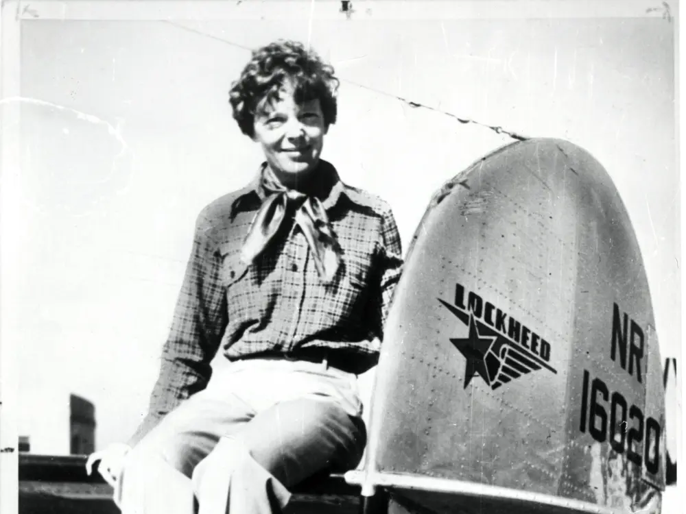 Earhart sitting next to a part of the Lockheed Electra aircraft
