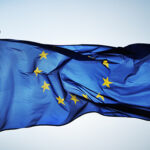 An image of the EU flag attached a flag pole flying.