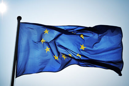 An image of the EU flag attached a flag pole flying.