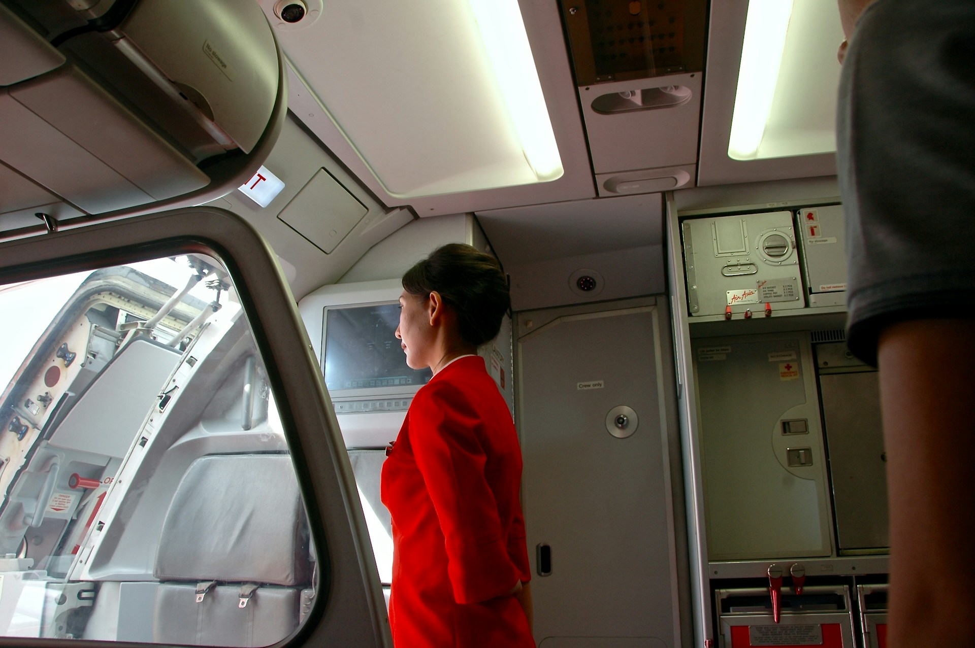 Flight attendant inside an aircraft facing the aircraft door