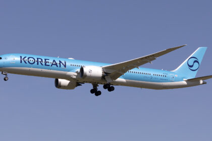A Korean Air aircraft mid-flight, with a blue sky as the background.