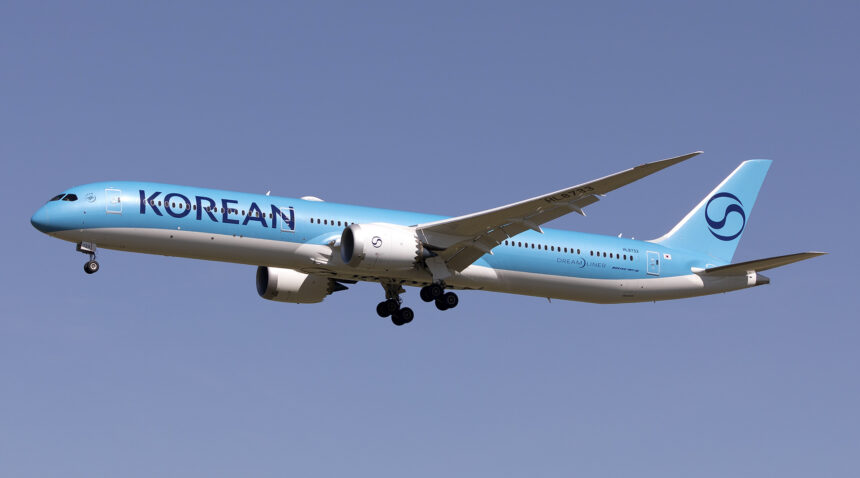 A Korean Air aircraft mid-flight, with a blue sky as the background.