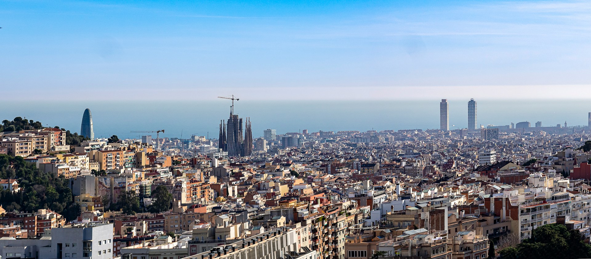 A panoramic view of Barcelona from a hillside under a clear blue sky