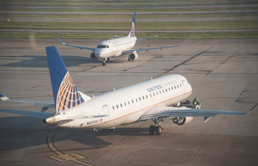 Two United Express commercial airplanes on an airport runway, one seen in the foreground in profile and the other in the background from the front.