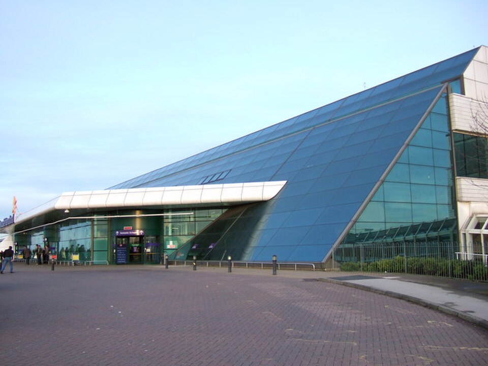 The exterior of Newcastle Airport's main building. People can be seen using the doorways and walking near the entrance. 