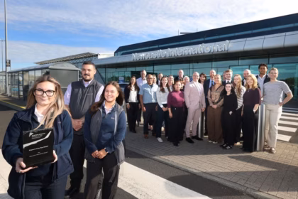 An image of a group of Newcastle Airport employees posed outside of the terminal at Newcastle Airport with their 'Airport of the Year' in the hands of the employee at the front of the group.