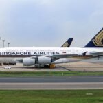 Photograph depicting the exterior of a Singapore Airlines Airbus A380 stationed at an airport terminal, ready for boarding.