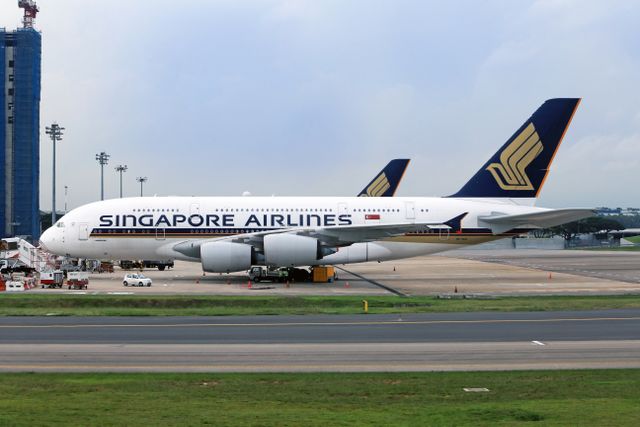 Photograph depicting the exterior of a Singapore Airlines Airbus A380 stationed at an airport terminal, ready for boarding.