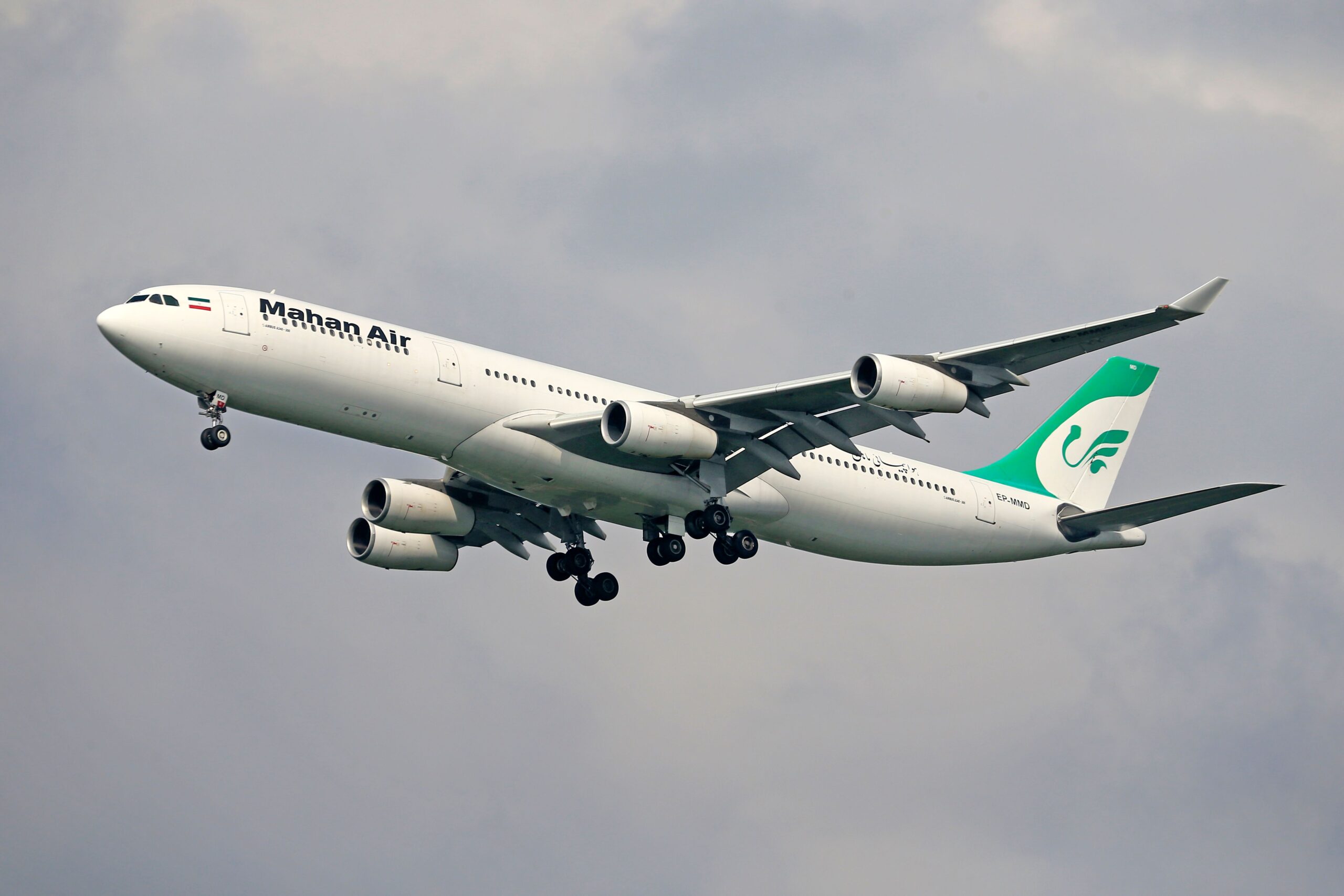 A Mahan Air commercial Airbus passenger plane in mid-flight against a cloudy sky