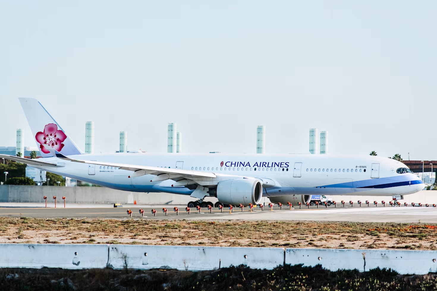 A photo of a China Airlines plane on the runway at an airport. The sky in the background is blue.