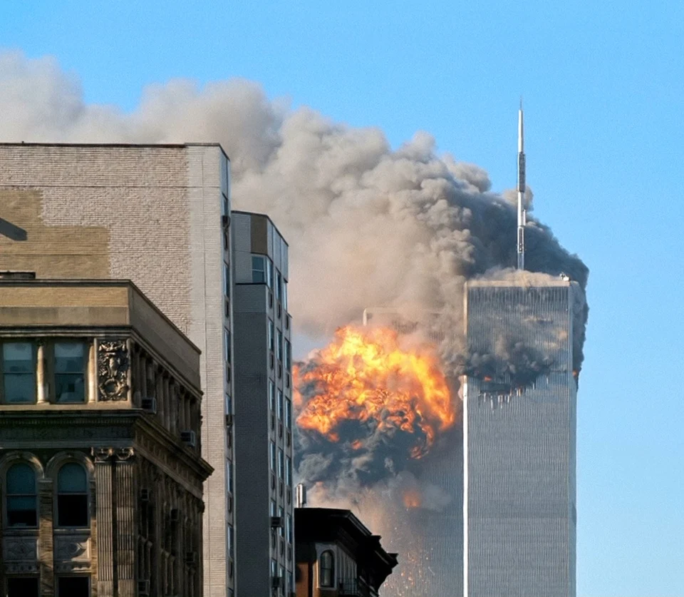 The image shows the moment the World Trade Center in New York City was hit by a hijacked plane during 9/11. Fire and smoke can be seen coming from the tall, sky-scraper building.