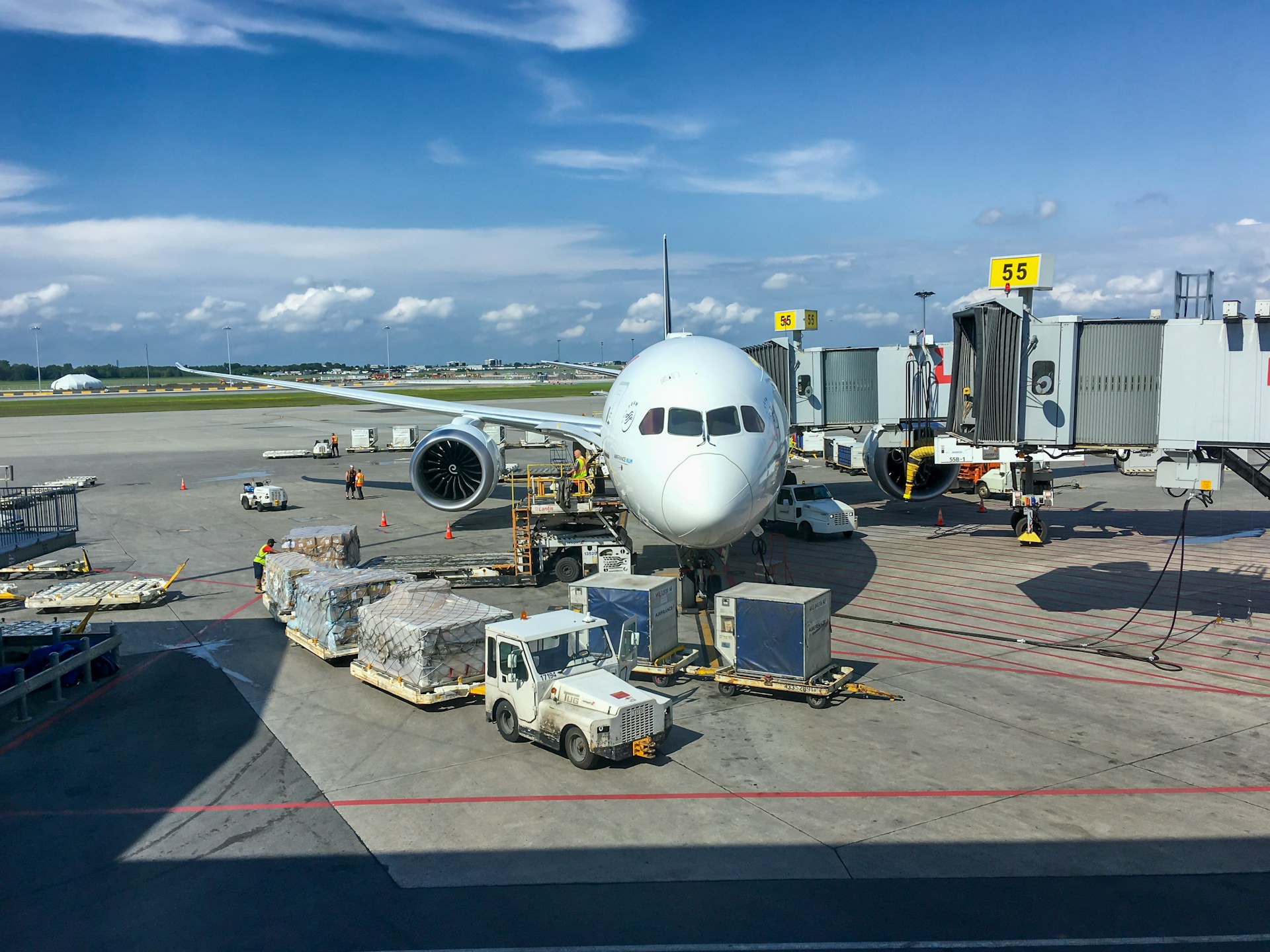 A plane on an airport tarmac with cargo being loaded to the airplane