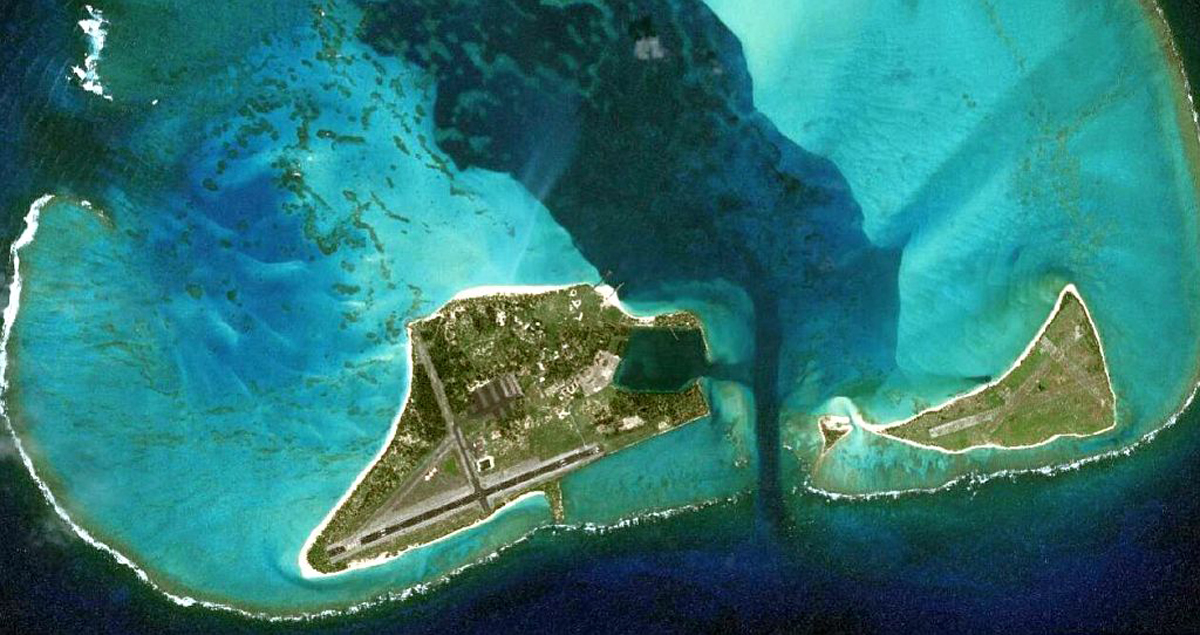 Aerial perspective of Midway Atoll with two smaller islands nearby, highlighting the vibrant landscape and ocean.