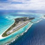 Aerial view of Midway Atoll, showcasing the island's runway and surrounding turquoise waters.